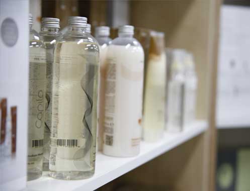 Clear treatment and shampoo bottles lined along a white showroom shelf