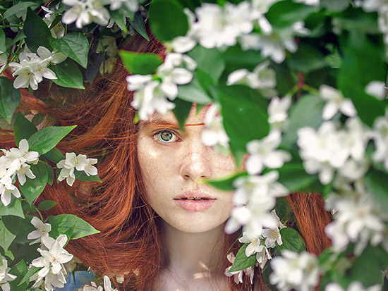 Woman with red hair among white blossom
