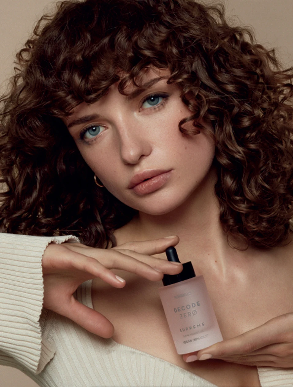 Decode Zero Supreme clean prodigy oil held by a model with curly hair.