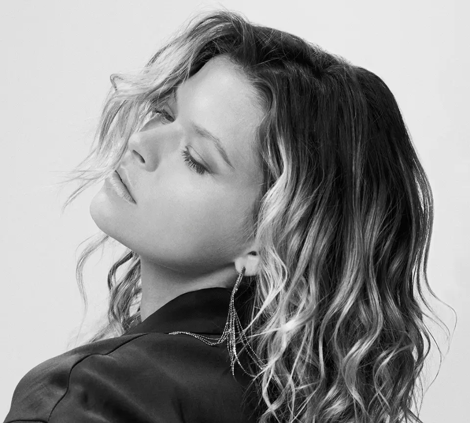Black and white side profile of a woman with wavy blonde hair and a statement earring.