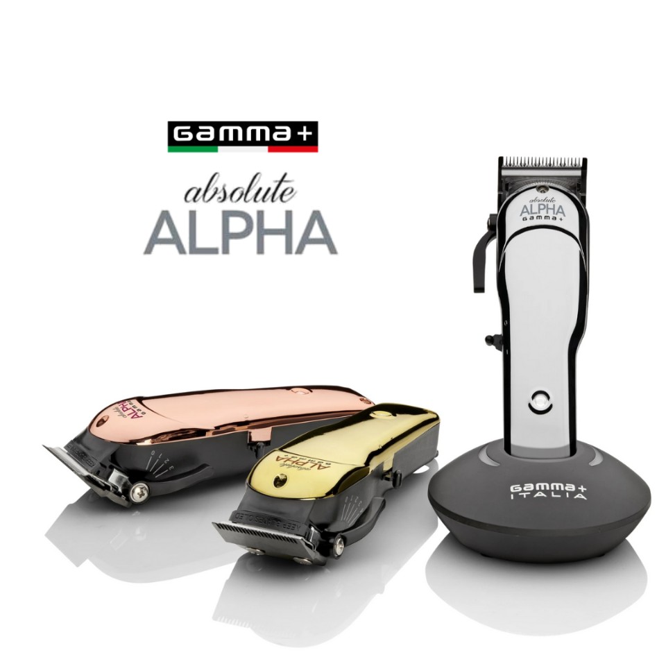 The Gamma+ Absolute Alpha clipper upright on its charging stand, with rose gold and gold bodied Alphas laid down beside it